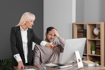 Confused employee and boss pointing at computer in office
