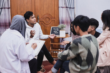 Young man telling a story while other listening at group counseling therapy session. 