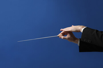 Professional conductor with baton on blue background, closeup