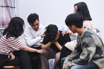 Group of people in counseling therapy session showing empathy and support sad friend. Team touching shoulder of desperate crying man.