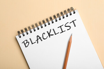 Word Blacklist written in notepad on beige background, top view
