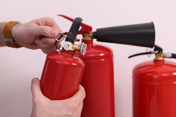 Naklejka premium Man checking quality of fire extinguishers indoors, closeup