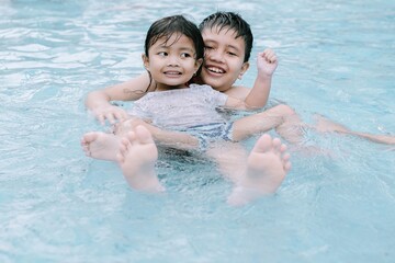 Two Southeast Asian children playing in the water at a swimming pool. Soft focus or unfocused.