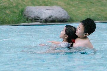 Two Southeast Asian children playing in the water at a swimming pool. Soft focus or unfocused.