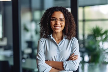 Smiling confident stylish young woman standing at the office. Young businesswoman, curly-haired lady executive business leader manager looking at camera arms crossed, generative AI - obrazy, fototapety, plakaty