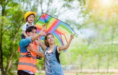 Asian young family playing kite together in park. Family having fun in park. Togetherness concept.