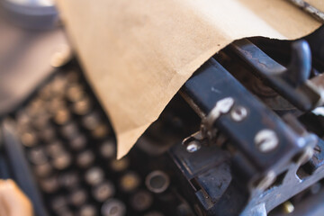 Vintage typewriter with Cyrillic alphabet characters keyboard, writing a text letter on empty page sheet of craft paper, old-fashioned writer machine, view of hands writing book and printing letters