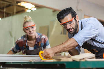 young carpenter man wear uniform and goggles working use electronic saw cutting wood. craftsman...