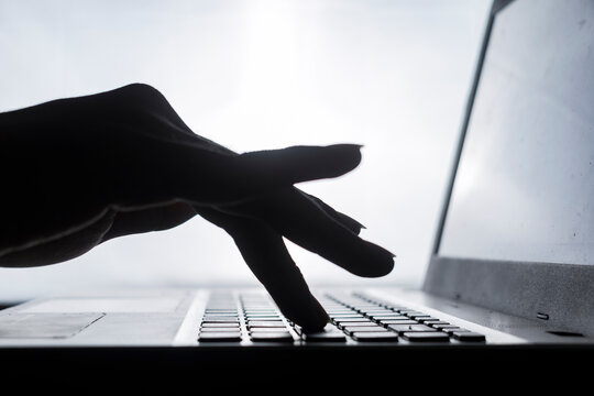 close up silhouette of man hand typing enter button keyboard laptop isolated on white background
