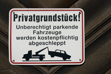Schild mit der Aufschrift Privatgrundstück, parkende Autos werden abgeschleppt