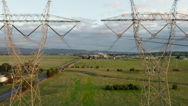 Dolly through high-voltage power line towers in LaTrobe Valley, Victoria. Overhead long-distance transmission wires distribute electricity to the grid using super high-voltage sub-transmission tech.