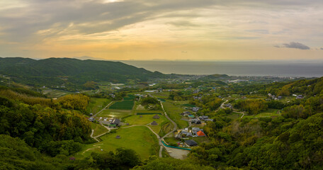 Panoramic aerial view of green fields and thatched huts in coastal landscape - 601247714