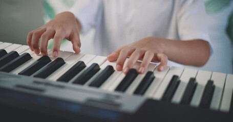 Close-up hand of Creative asian boy with artistic skills taking music lessons online during a video call and playing the piano at home. Music, hobby and lifestyle concepts.