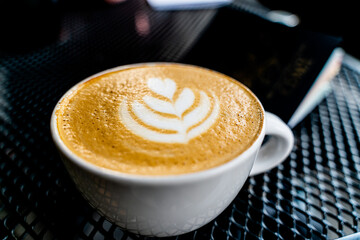 cappuccino mug with foam and a book on the side