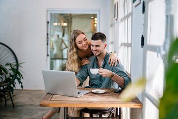 Smiling couple looking at laptop together at cozy home office. The concept of couples sharing one idea together.