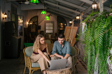 Loving young couple looking at laptop together at cozy home office. The concept of couples sharing one idea together..