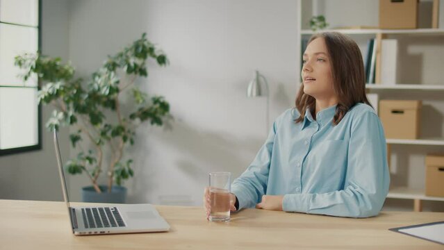 Female Office Worker Drink a Glass of Clean Water. A Smiling Woman Start New Day with a Healthy Life Habit, Holding a Glass Drinking Clean Mineral Natural Water. Lifestyle Healthcare Concept.