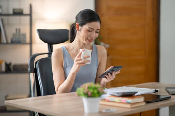 Young Asian businesswoman reading graphs and talking on phone with customers in office