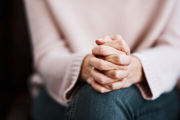 Woman, hands together and closeup with stress and anxiety in therapy for psychology crisis. Pray, mental health and problem with hand of a female patient scared with depression at counselling on sofa