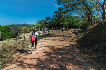 female hiker walking on a dirt road surrounded by nature and countryside in Puntarenas of Costa Rica