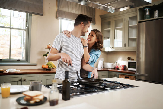 Love, food and cooking with couple in kitchen and hugging for breakfast, morning and happiness. Smile, care and nutrition with man and woman eating at home for happy, health and hungry together