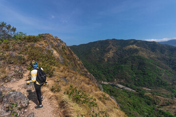 Obraz premium young hiker man with red backpack walking through a landscape of green mountains full of nature and countryside on a hot sunny day in the province of Puntarenas in Costa Rica