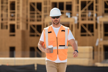 Builder in helmet on coffee break at construction site american wood frame house construction. Man worker with helmet on construction site. Bilder in hardhat.