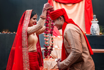 Celebration, young Indian married couple happy and at wedding or special event. Festival or romance, culture or marriage and smiling people with woman putting necklace on man neck with veil.