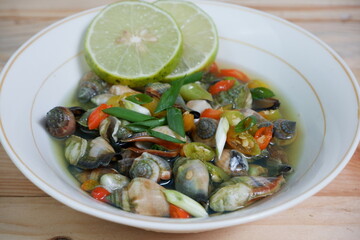 selective focus on white bowl serving sea snail or Laevistrombus canarium in Indonesian is called siput gonggong. soft focus