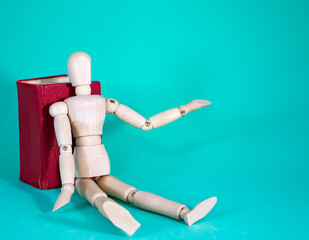 Wood Man and Book. Wooden Figure Sitting. Cheerful Wooden Doll on a Blue Background with a Book. Reading Books Shows Learning.