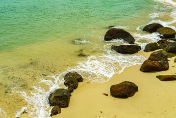 Ocean beach with yellow sand and large rocks