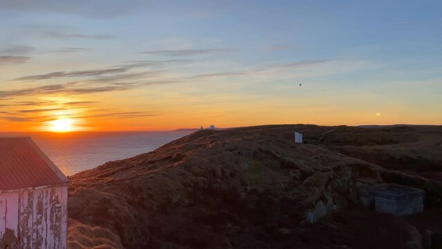 Wide shot of a helicopter flying closer in silhouette over a remote island near the Russian border