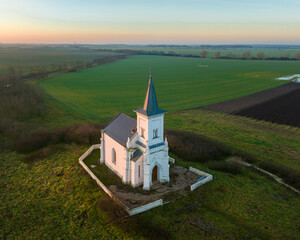 Small white chapel in alone in the fileds with scenic sunrise colored sky.