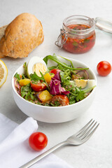 Salad with boiled eggs, cherry tomatoes, aragula, cabbage and potatoes.