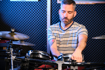 Man adjusting a drum in a drum set in a recording studio.