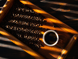 coffee with coffee beans in brown wooden background with morning sun lights