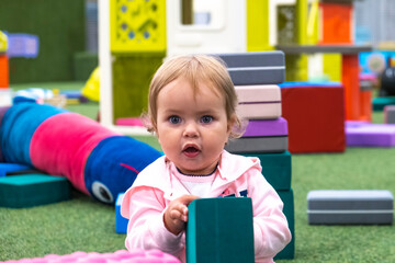 Pretty little girl plays in children's room in mall. 