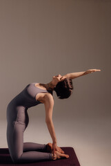 Young pregnant woman doing yoga exercises and meditating at studio. Health care, mindfulness and wellness concept.