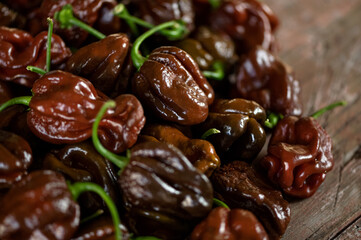 Chocolate hot habanero pepper. Lot of ripe peppers on wooden surface. Pepper harvest. Bright spices. Spicy food. Mexican pepper. Wooden background. Close-up. Soft focus. Top view. 