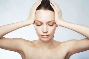 Naklejka premium Woman, beauty and hands on head for hair care, skincare or cosmetics treatment on gray studio background. Girl, face and closed eyes to relax at spa for scalp, body and facial massage or selfcare