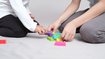 Children play with colorful plastic bricks while sitting on the floor. The kid has fun and builds from the constructor cubes. Early learning. Educational toys.