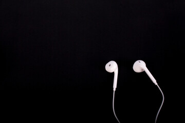 White earphones for mobile phone on black background