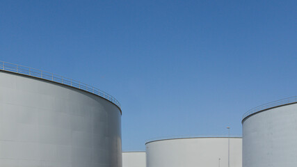 three large oil tanks against the blue sky with space for text