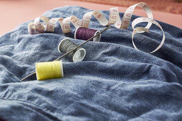 needles measuring tape and thread on the background of torn jeans the concept of reasonable consumption of needlework for small businesses