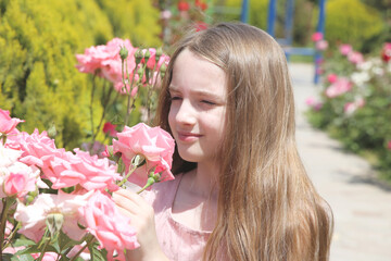 Little girl among flowerbed of pink roses
