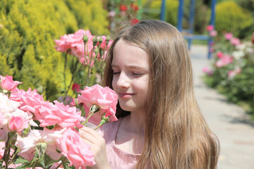 Naklejka premium Little girl among flowerbed of pink roses