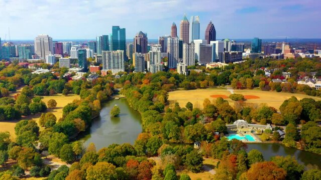 Aerial drone shot circling around Piedmont Park with downtown Atlanta, Georgia in the background. A lake, swimming pool, tennis courts, and softball fields are shown below.