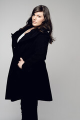 Woman, fashion and portrait of plus size model posing in winter clothing against grey studio background. Isolated female person standing with stylish black coat or warm fashionable clothes for beauty
