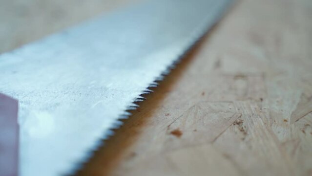 A hand saw for wood with fine teeth lies on an osb plate close-up