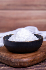Coconut powder. Grounded coconut flakes on wood floor. Dark bowl of dessicated coconut. Close up
